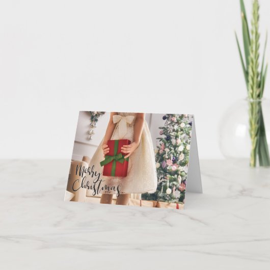 Meisje met verpakt geschenk bij de kerstboom kaart (Voorkant)