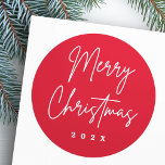 Merry Christmas handgeschreven script rood Ronde Sticker<br><div class="desc">Vrolijk kerstfeest stickers met de tekst "Vrolijk kerstfeest" in een handgeschreven stijl script lettertype op een rode achtergrond met het jaar of aangepaste tekst hieronder.</div>