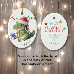 Merry Dinosaur Kinder kerst Keramisch Ornament<br><div class="desc">Aan de voorkant van dit keramische siermiddel voor een kind is een schattige baby dinosaurus met een kersthoed. Hij heeft een kerstboombol tussen zijn voeten en een cadeaupakket naast hem. Er is een reeks Holiday-lichten achter hem. De naam van je kind is donkergroen rechts onderaan. De achterkant van de versiering...</div>