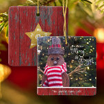 Merry en Bright Cute Rustic Snowman Tree Keepslag Keramisch Ornament<br><div class="desc">"Moge je dagen vrolijk en helder zijn." Een close-up foto van een gelukkige en schattige, rustige sneeuwman, gewikkeld in een rode en witte gestreepte sjaal tegen aangestoken bomen helpt je met kerst en nieuwjaar te gebruiken. Op de achterkant bedekt een gouden faux glitter ster donkerrood schuurhout. Voel de warmte en...</div>