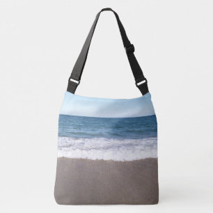 Milde golven die over het zandstrand spoelen crossbody tas