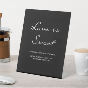 Minimalistische kalligrafie liefde is zoete zwarte reclamebord met voetstuk