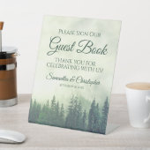 Mistige groene dennenbomen onderteken ons gastenbo reclamebord met voetstuk (Insitu)