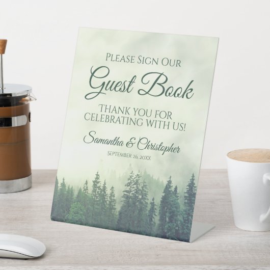 Mistige groene dennenbomen onderteken ons gastenbo reclamebord met voetstuk (Insitu)