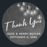 Modern Chalkboard & Edison Lights Dank u Ronde Sticker<br><div class="desc">In dit bruiloft-thema ontwerp heb ik een elegant, modern kalligrafie lettertype gebruikt om een witte grafische typografie overlay voorlezen te creëer. De achtergrond werd bedekt met een afbeelding met een getextureerd krijtbord. Bedekken dat is een cluster van ronde witte Edison lichten. Vul de sjabloon blanks in met uw gegevens om...</div>