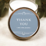 Modern Deco | Elegant Dusty Blue en White Wedding Ronde Sticker<br><div class="desc">Deze glamoureuze trouwstickers zijn voorzien van een moderne spion op een klassiek kunstdeco. De ,  witte geometrische grenzen en de versiering versieren een elegante stoffige blauwe achtergrond voor een dramatische,  vintage bruiloft blik. Klassieke witte typografie zegt "dank je",  waardoor deze perfect zijn om je huwelijksgunsten aan te vullen.</div>