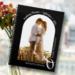 Modern Photo Arch Black Wedding Planner<br><div class="desc">Een elegante spiraalverbindende planner met 60 pagina's en 12 maanden, kenmerkt één enkele verticale of portretgeoriënteerde trouwfoto in een unieke arched lay-out. KIES SOFT OF HARD HOESJE. Je namen zijn verbonden met een grote witte ampersand onderaan en je trouwdatum bovenaan. Verander de kleur van de dekking om uw foto aan...</div>