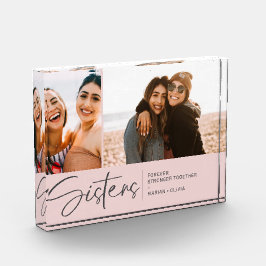 Moderne zusters houden twee foto's bloost roze