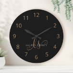 Moderne zwarte goudfilm, afgebeeld in script ronde klok<br><div class="desc">Modern Black Gold Feminine Script Monogrammed Large Clock. Pas deze moderne elegante klok eenvoudig aan met uw eigen monogram en naam.</div>