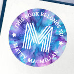 Monogram initiaal blauw paarse kinder boeklabel ronde sticker<br><div class="desc">Boekplaatlabels met uw monogram initiaal en aanpasbare tekst "dit boek behoort toe" en jouw namen op een blauw en paarse patroonachtergrond.</div>