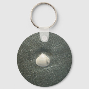 Mooie zeeschelp in het zand: een zout souvenir sleutelhanger