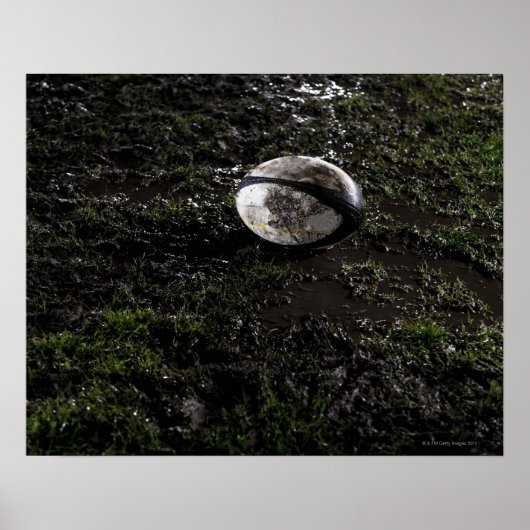 Muddy rugby ball zit op een kauwgras. poster (Voorkant)