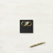 Oneindigheid met gouden pauwenveer post-it® notes (Op bureau)