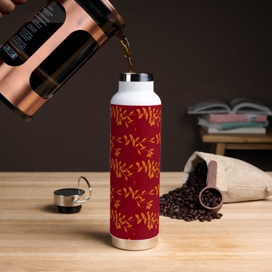 Oranje silhouetbladeren op rood waterfles (Koffie)