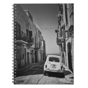 Oude auto in een straat in Italië met zee Notitieboek