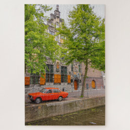Oude oranje auto langs een Amsterdamse gracht Legpuzzel