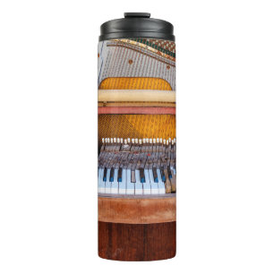 Oude  piano met het deksel eraf. Een vervallen Thermosbeker