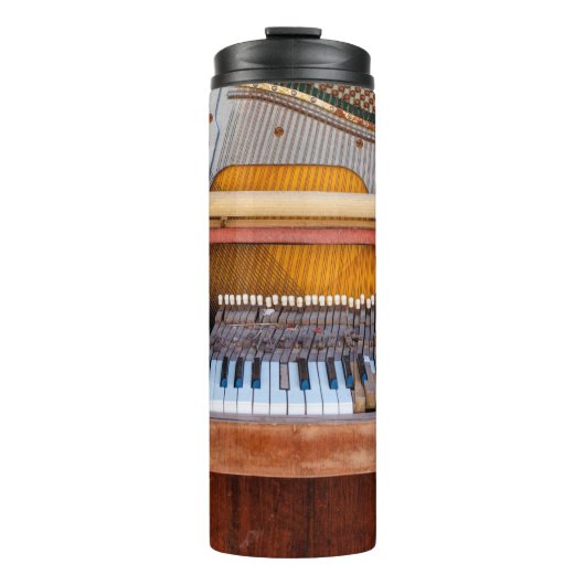 Oude piano met het deksel eraf. Een vervallen Thermosbeker (Voorkant)