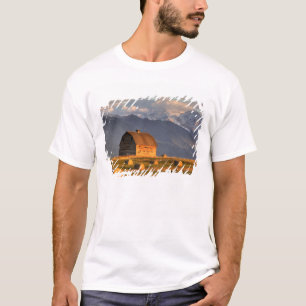 Oude schuur omlijst door hooibalen en dramatisch t-shirt