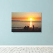 Paar zit op strand op Sunset Canvas print (Insitu (Houten vloer))
