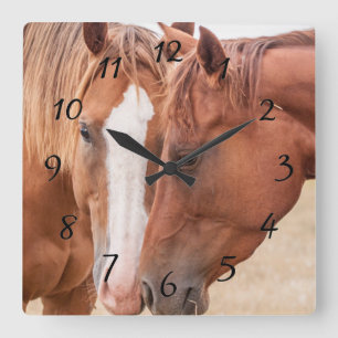 Paarden die elkaar in een wei knuffelen vierkante klok