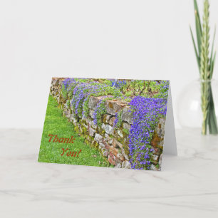 Paarse bloemen die over de stenen muur vallen, dan bedankkaart