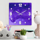 Paarse Waterverf Abstract met Gold Glitter Stars Vierkante Klok<br><div class="desc">Kleine gouden sterren draaien op een paarse en donkerblauwe abstracte achtergrond. Verleen uw favoriete kamer met deze verbluffende,  levendige wandklok. Uw keuze uit een rond of vierkant klokgezicht. Maakt een geweldig cadeau voor het huishouden! U kunt deze muurklok gemakkelijk personaliseren. Stuur me alstublieft alle vragen of verzoeken.</div>