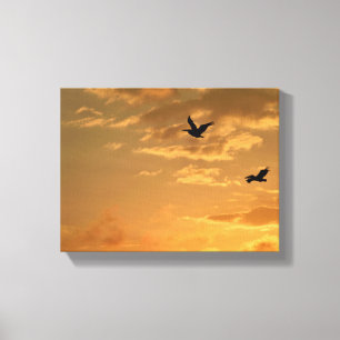 Pelikanen vliegen bij zonsondergang canvas afdruk