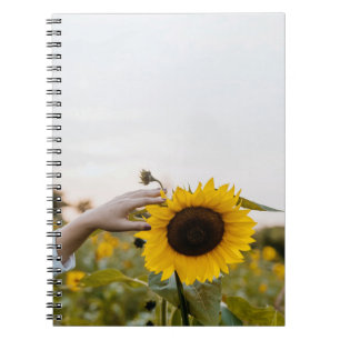 Persoon die zonnebloem houdt notitieboek