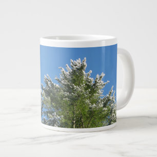 Pijnboom met sneeuwklemmen op blauwe hemel grote koffiekop