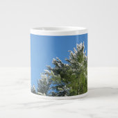 Pijnboom met sneeuwklemmen op blauwe hemel grote koffiekop (Voorkant)