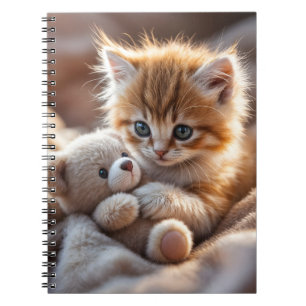 Pluizig rood katje speelt met een kleine teddybeer notitieboek