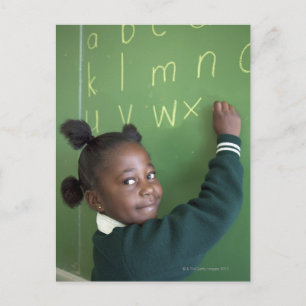 Portret van glimlachend schoolmeisje dat op de briefkaart