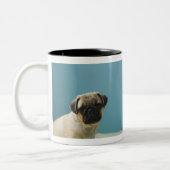 Pug puppy op bed naast de telefoon en tweekleurige koffiemok (Links)