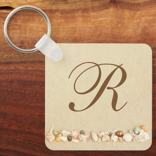 Rij zeeshells op strand zand met monogram sleutelhanger (Voorkant)