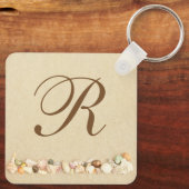 Rij zeeshells op strand zand met monogram sleutelhanger (Achterkant)