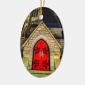 Rode deur naar de kerk met maan keramisch ornament (Links)