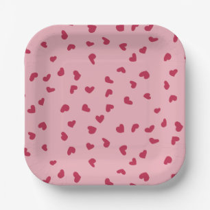 Rode hartjes verspreid over roze papieren bordje