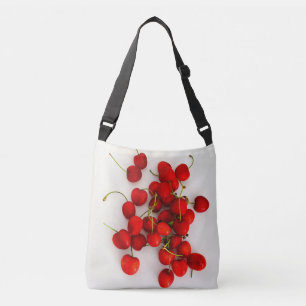 Rode kersen in natuurlijk licht liggen op wit crossbody tas
