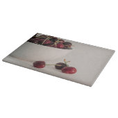 Rode kersenvruchten witte kom in gedempte tonen fo snijplank (Hoek)