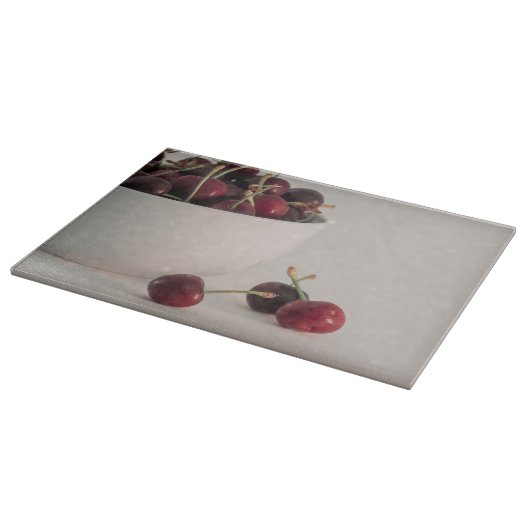 Rode kersenvruchten witte kom in gedempte tonen fo snijplank (Hoek)