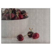 Rode kersenvruchten witte kom in gedempte tonen fo snijplank (Voorkant)