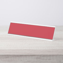 Rode, roze en oranje kledingstukken hangen naast e bureau naambordje