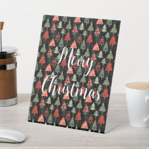 Rood & groen geplakte kerstbomen op zwart reclamebord met voetstuk