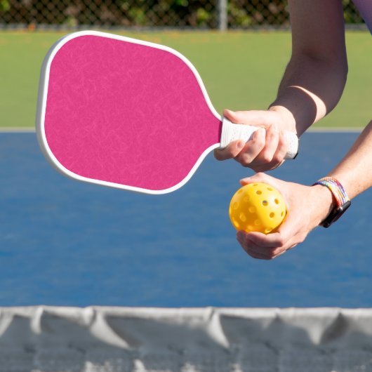 Rosa gestructureerd oppervlak met subtiel draaiend pickleball paddle (Insitu)