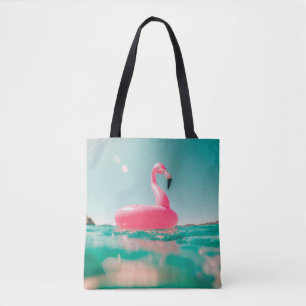 Roze flamingo zwemring op waterlichaam in zomer tote bag