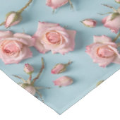 Roze rozen verspreid over een lichtblauwe achtergr tafelkleed (Gekanteld)