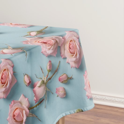 Roze rozen verspreid over een lichtblauwe achtergr tafelkleed (Voorbeeld)