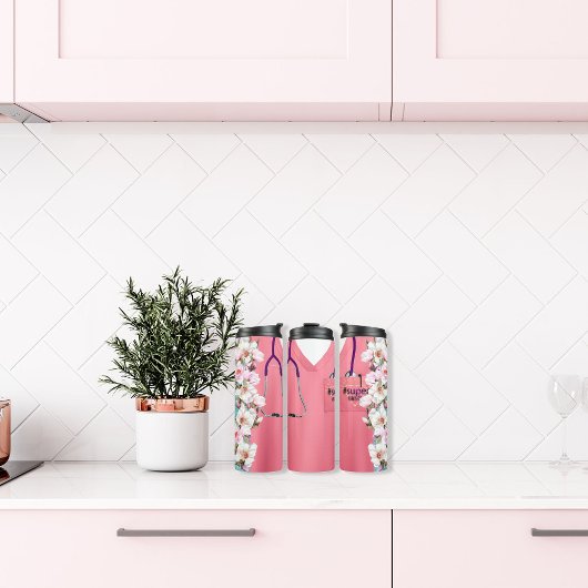 Roze scrubs met bloemontwerp en stethoscoop thermosbeker