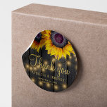 Rustiek hout zonnebloem bruiloft dank u gunst ronde sticker<br><div class="desc">Bewerkbare tekst bruiloft dank u sticker met rustieke grote mooie zonnebloemen op een donkerbruine schuur houten achtergrond met string verlichting. Ideaal voor uw zomer of herfst herfst elegante rustieke landelijke buitentuin of boerderij bruiloft.         Personaliseer het met de namen van de bruid en bruidegom en de trouwdetails!</div>